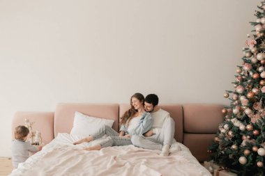 Mutlu bir aile yatakta birlikte gülüyor ve eğleniyor. İki ebeveyn evde oğluyla oynuyor. Anne ve baba hafta sonları çocuklarıyla kaliteli zaman geçiriyorlar. Bir serinin parçası.