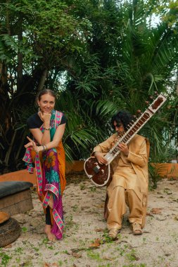 Indian musician in traditional clothes playing sitar festive season outdoor home. Smiling young woman in traditional saree dancing and enjoy festival. Happy Diwali greeting photo. Part of a series. clipart