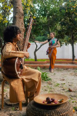 Indian musician in traditional clothes playing sitar festive season outdoor home. Happy Diwali greeting photo. Part of a series. clipart