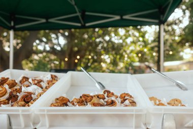 Tarçınlı çörek ya da tarçınlı tarçın. Beyaz ahşap arka planda beyaz krema soslu ev yapımı tatlı tatlı çörekler..