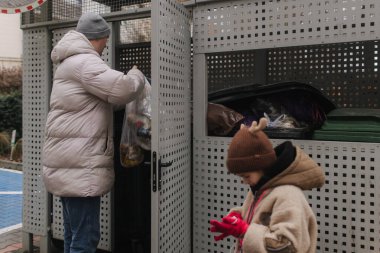 Alfa ve Sıfır jenerasyonu atık. Kızları olan baba çöp tenekelerine çöp atıyor. Ebeveynler çöp toplamaya ve ayırmaya yardım ediyorlar, plastik atık yönetimine odaklanıyorlar. Bir serinin parçası.