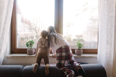 Çocuk evde otururken pencereden dışarı bakar. Isıtma konsepti yok. Jenerasyon alfa kavramı. Bir serinin parçası.