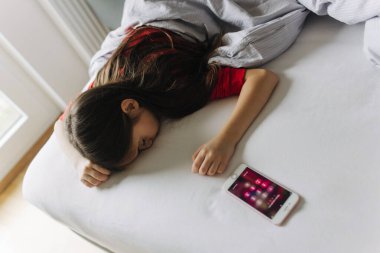 Yatakta yorganın altında yatan güzel bir genç kız. Sabah erken kalkmak, yatılı okul. Alarm onu uyandırıyor. Yeni nesil alfa ve yeni gün konsepti. Bir serinin parçası