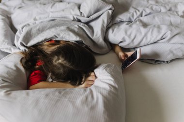 Yatakta yorganın altında yatan güzel bir genç kız. Sabah erken kalkmak, yatılı okul. Alarm onu uyandırıyor. Yeni nesil alfa ve yeni gün konsepti. Bir serinin parçası