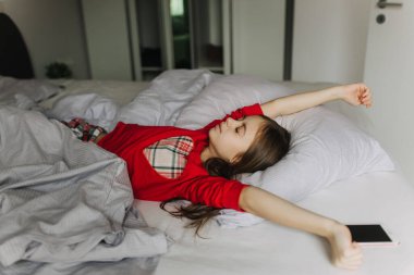 Yatakta yorganın altında yatan güzel bir genç kız. Sabah erken kalkmak, yatılı okul. Alarm onu uyandırıyor. Yeni nesil alfa ve yeni gün konsepti. Bir serinin parçası