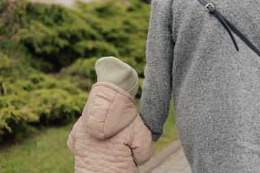 Anne kızıyla birlikte dışarıda, yakın plan. Soğuk mevsimde bir kadın ve bir çocuk parkta yürüyorlar. Tek başına ebeveynlik ve çocuk yetiştirme kavramı. Bir serinin parçası