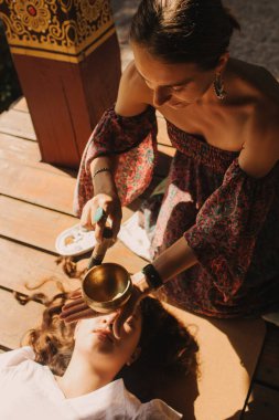 Düşünceli meditasyon ve çardakta yoga yapmadan önce kadın akıl hocası ve öğrenciyi kapatın. Meditasyon deneyimini kolaylaştırmak. Dizinin bir parçası. Tibet şarkı kasesi. Yumuşak odak, bulanık, gürültü efekti