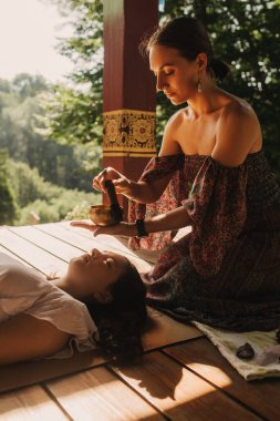 Düşünceli meditasyon ve çardakta yoga yapmadan önce kadın akıl hocası ve öğrenciyi kapatın. Meditasyon deneyimini kolaylaştırmak. Dizinin bir parçası. Tibet şarkı kasesi. Yumuşak odak, bulanık, gürültü efekti