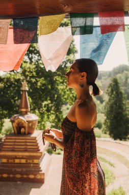 Bir Budist tapınağında yoga ve meditasyon yapan bir kadın, kapalı gözlerle rahatlamış. Dikkatli meditasyon konsepti. Sağlıklı olmak. Odak bulanıklığı ve gürültü etkisi yok. Dizinin bir parçası.