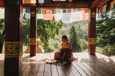 Bir Budist tapınağında yoga ve meditasyon yapan bir kadın, kapalı gözlerle rahatlamış. Dikkatli meditasyon konsepti. Sağlıklı olmak. Odak bulanıklığı ve gürültü etkisi yok. Dizinin bir parçası.