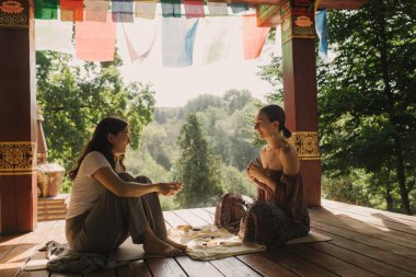 Düşünceli meditasyon ve çardakta yoga yapmadan önce kadın akıl hocası ve öğrenciyi kapatın. Meditasyon deneyimini kolaylaştırmak. Dizinin bir parçası. Tibet şarkı kasesi. Yumuşak odak, bulanık, gürültü efekti