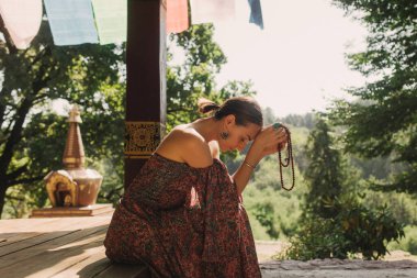 Bir Budist tapınağında yoga ve meditasyon yapan bir kadın, kapalı gözlerle rahatlamış. Dikkatli meditasyon konsepti. Sağlıklı olmak. Odak bulanıklığı ve gürültü etkisi yok. Dizinin bir parçası.