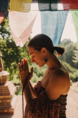 Bir Budist tapınağında yoga ve meditasyon yapan bir kadın, kapalı gözlerle rahatlamış. Dikkatli meditasyon konsepti. Sağlıklı olmak. Odak bulanıklığı ve gürültü etkisi yok. Dizinin bir parçası.
