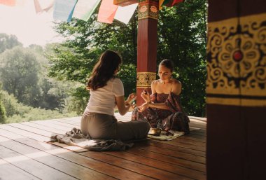 Düşünceli meditasyon ve çardakta yoga yapmadan önce kadın akıl hocası ve öğrenciyi kapatın. Meditasyon deneyimini kolaylaştırmak. Dizinin bir parçası. Tibet şarkı kasesi. Yumuşak odak, bulanık, gürültü efekti