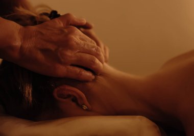 Masaj masasında yatan genç bir kadının boynuna bir masörün elleri masaj yapıyor. Fizyoterapi konsepti, boyun basınç noktası. Sağlıklı olmak. Odak bulanıklığı yok. Dizinin bir parçası.