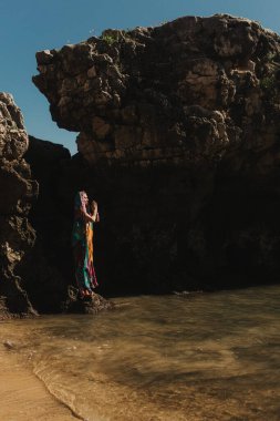 Geleneksel sari elbiseli Hintli kadın arka planda okyanusla birlikte doğada dua ediyor. Hint festivali kostümü. Yalnız turizm kavramı ve Hindistan 'a seyahat. Bir serinin parçası