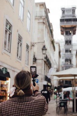 Vlogger gezgini kadın, uygulama seyahati ile telefon paylaşımına video kaydediyor. Lizbon 'un merkezindeki gözlem güvertesine asansörde sosyal medya hikayeleri çeken orta yaşlı bir kadın. UGC