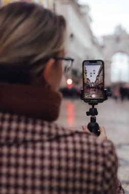 Lizbon 'a seyahat tatilini uygulayarak bir kadının eline telefon görüşmelerini kaydet. Kadın nüfuzlu biri, Ticaret Meydanı 'na giden yolda sosyal medya hikayeleri çekiyor. UGC