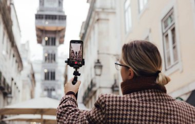 Vlogger gezgini kadın, uygulama seyahati ile telefon paylaşımına video kaydediyor. Lizbon 'un merkezindeki gözlem güvertesine asansörde sosyal medya hikayeleri çeken orta yaşlı bir kadın. UGC