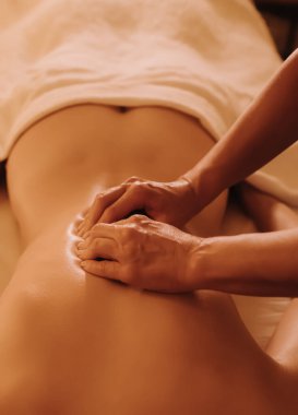 Masaj masasında yatan genç bir kadının omuzlarına masaj yapan kadın masörlerin elleri. Fizik tedavi konsepti, boyun basınç noktası. Dizinin bir parçası. Yumuşak odaklı, bulanık