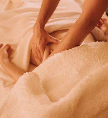 Masaj masasında yatan genç bir kadının göbeğine masaj yapan kadın masörlerin elleri. Fizik tedavi konsepti, boyun basınç noktası. Dizinin bir parçası. Yumuşak odaklı, bulanık