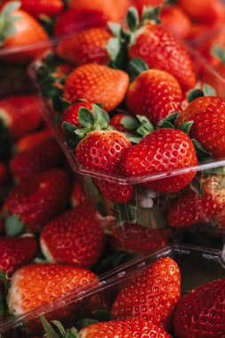 Taze böğürtlen dolu şeffaf plastik konteynırlar. Yerel bir pazarda paketler üst üste istiflenir. Meyveler sert, zengin ve canlı. Dizinin bir parçası