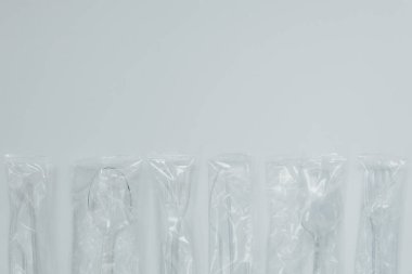 Plastik kaseleri ve kaşıkları hafif arka planda harcayın. Atık minimize etme, plastik geri dönüşüm endüstrisi ve tüketim kavramı. Metin için yer alan arkaplan, Üst Görünüm. Bir serinin parçası