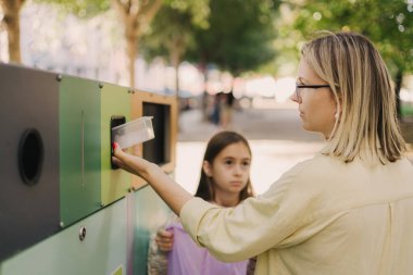 Annem Alfa Güzeli 'ne atık kutularının yakınındaki çöpleri ayırmayı öğretiyor. Plastik, kağıt, cam, e-atık torbasını tekrar kullanılmak üzere kovaya atıyorum. İklim değişikliğine yardım ve temiz çevre yeşili kavramı israf değil