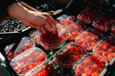 Yerel bir markette plastik ambalajda taze ahududu ile yakın plan çekilmiş. Organik ürünler açık pazarda satılıyor. Taze ekin ve sebze hasadı satıyorum. Dizinin bir parçası