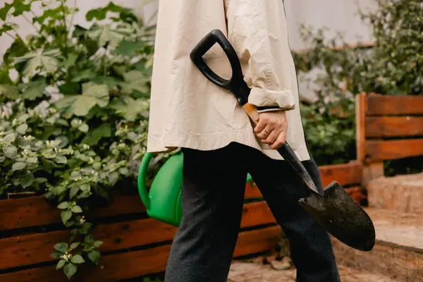 Bahçedeki eko-çiftlikte çiçeklerle ve bitkilerle ilgilenen çiçekçi olarak bahçe aletleri olan bir kadının yakın çekimi. Yeşil turizm kavramı, yavaş yaşam, bahçıvanlık, çevre dostu. Dizinin bir parçası