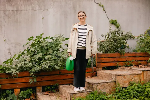 Çiçekçilik yapan orta yaşlı bir kadının portresi. Bahçedeki çiçek ve bitkilerle ilgilenen. Klasik sera eko-çiftliği. Yeşil turizm kavramı, yavaş yaşam, bahçıvanlık, çevre dostu. Dizinin bir parçası