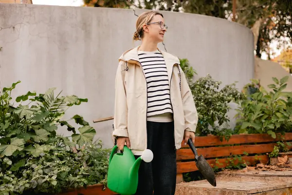 Çiçekçilik yapan orta yaşlı bir kadının portresi. Bahçedeki çiçek ve bitkilerle ilgilenen. Klasik sera eko-çiftliği. Yeşil turizm kavramı, yavaş yaşam, bahçıvanlık, çevre dostu. Dizinin bir parçası