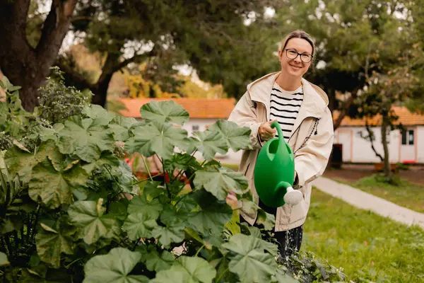 Çiçekçilik yapan orta yaşlı bir kadının portresi. Bahçedeki çiçek ve bitkilerle ilgilenen. Klasik sera eko-çiftliği. Yeşil turizm kavramı, yavaş yaşam, bahçıvanlık, çevre dostu. Dizinin bir parçası