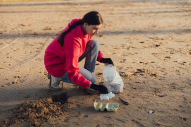 Kadın bir çevre bilimci plastikten ve diğer atıklardan sahili temizliyor. Çöp geri dönüşümü ve çevresel bakım kavramı. Bir serinin parçası