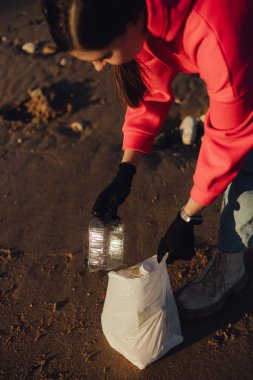 Kadın bir çevre bilimci plastikten ve diğer atıklardan sahili temizliyor. Çöp geri dönüşümü ve çevresel bakım kavramı. Bir serinin parçası