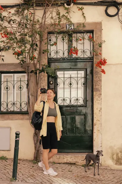 Gözlem güvertesindeki orta yaşlı gezgin kadın Portekiz 'deki Lizbon manzarasının güzel bir kamerasıyla fotoğraf çekiyor. Seyahat ve solo turizm konsepti. Dizinin bir parçası.