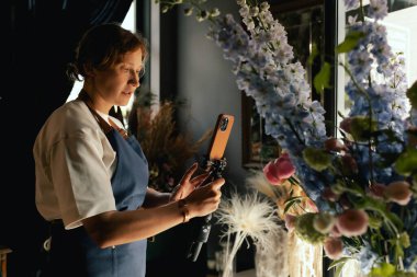 Küçük çiçekçi dükkanı. Bir kadın video blogu ya da çevrimiçi kurs yazar. Çiçek okulu konsepti. Çiçekçi kadın çiçek aranjmanı yapar. - Evet. Yerel bir iş. Bir serinin parçası.