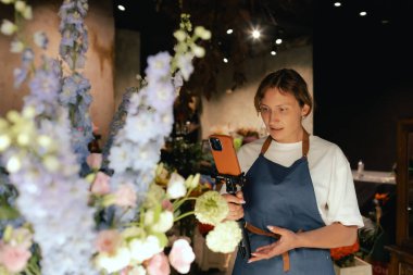 Küçük çiçekçi dükkanı. Bir kadın video blogu ya da çevrimiçi kurs yazar. Çiçek okulu konsepti. Çiçekçi kadın çiçek aranjmanı yapar. - Evet. Yerel bir iş. Bir serinin parçası.