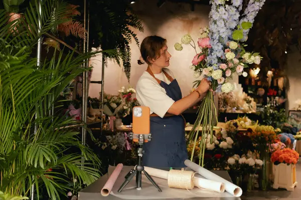 Küçük çiçekçi dükkanı. Bir kadın video blogu ya da çevrimiçi kurs yazar. Çiçek okulu konsepti. Çiçekçi kadın çiçek aranjmanı yapar. - Evet. Yerel bir iş. Bir serinin parçası.
