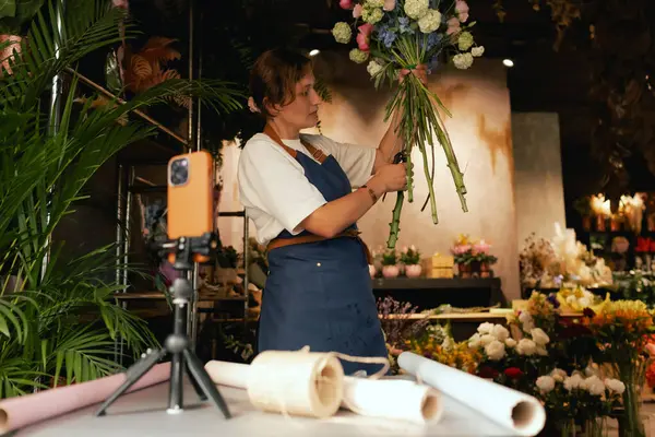 Küçük çiçekçi dükkanı. Bir kadın video blogu ya da çevrimiçi kurs yazar. Çiçek okulu konsepti. Çiçekçi kadın çiçek aranjmanı yapar. - Evet. Yerel bir iş. Bir serinin parçası.