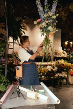 Küçük çiçekçi dükkanı. Bir kadın video blogu ya da çevrimiçi kurs yazar. Çiçek okulu konsepti. Çiçekçi kadın çiçek aranjmanı yapar. - Evet. Yerel bir iş. Bir serinin parçası.
