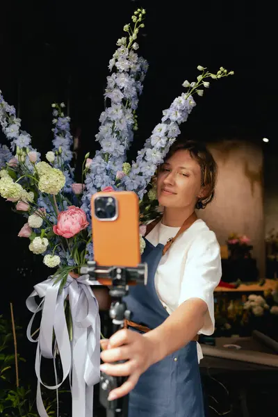 Küçük çiçekçi dükkanı. Bir kadın video blogu ya da çevrimiçi kurs yazar. Çiçek okulu konsepti. Çiçekçi kadın çiçek aranjmanı yapar. - Evet. Yerel bir iş. Bir serinin parçası.