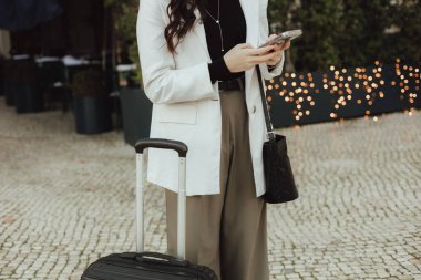 Elinde telefonu olan ve seyahate hazırlanan, Lizbon 'daki tren istasyonunun girişinde duran genç bir bayana yakın durun. İş seyahati ve bireysel turizm kavramı