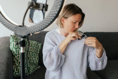 Orta yaşlı kadın güzellik blogcusu evde halka ışığıyla boks yaparken cilt bakımı yapıyor. Çevrimiçi mağaza tanıtımı için kullanıcı kaynaklı UGC içeriği. Vlogger canlı yayın yapıyor. Bir serinin parçası