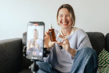 Orta yaşlı kadın güzellik blogcusu evde halka ışığıyla boks yaparken cilt bakımı yapıyor. Çevrimiçi mağaza tanıtımı için kullanıcı kaynaklı UGC içeriği. Vlogger canlı yayın yapıyor. Bir serinin parçası