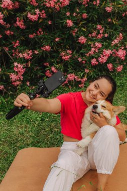 Corgi 'nin seyahat izni uygulaması üzerinden telefon görüşmesinde video kaydı yapan genç bir kız. Gen Z etkileyicisi sosyal medya hikayeleri çekiyor. Bir köpekle insan arasındaki arkadaşlık kavramı. Dizinin bir parçası. UGC