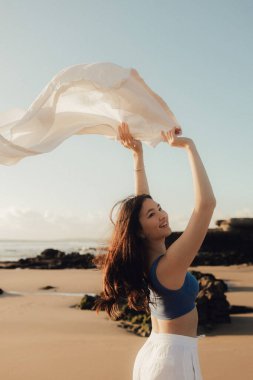Kumsalda, okyanusta, doğayla bütünleşen, sağlıklı bir hayat tarzı olan neşeli, özgür bir kadın. Sağlık hizmeti egzersizi ve yoga konsepti. Solo turizm. Bir serinin parçası.