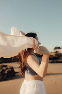 Kumsalda, okyanusta, doğayla bütünleşen, sağlıklı bir hayat tarzı olan neşeli, özgür bir kadın. Sağlık hizmeti egzersizi ve yoga konsepti. Solo turizm. Bir serinin parçası.