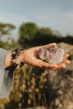 Doğal iyileştirici taşları tutan kadın ellerinin yakın çekimi. Enerji dengesi için araçlar, duygusal destek, niyet, sezgi, nazik varlık yoluyla kendini keşfetme. Klasik ton. Yumuşak odaklı, bulanık.