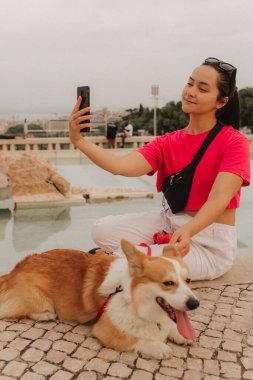Corgi 'nin seyahat izni uygulaması üzerinden telefon görüşmesinde video kaydı yapan genç bir kız. Gen Z etkileyicisi sosyal medya hikayeleri çekiyor. Bir köpekle insan arasındaki arkadaşlık kavramı. Dizinin bir parçası. UGC